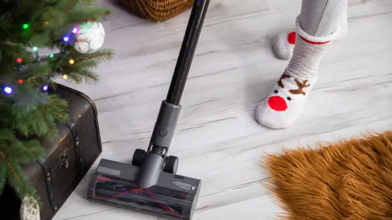 Person in festive socks vacuuming the living room floor near a Christmas tree, completing a task on their Pre-Christmas cleaning checklist.