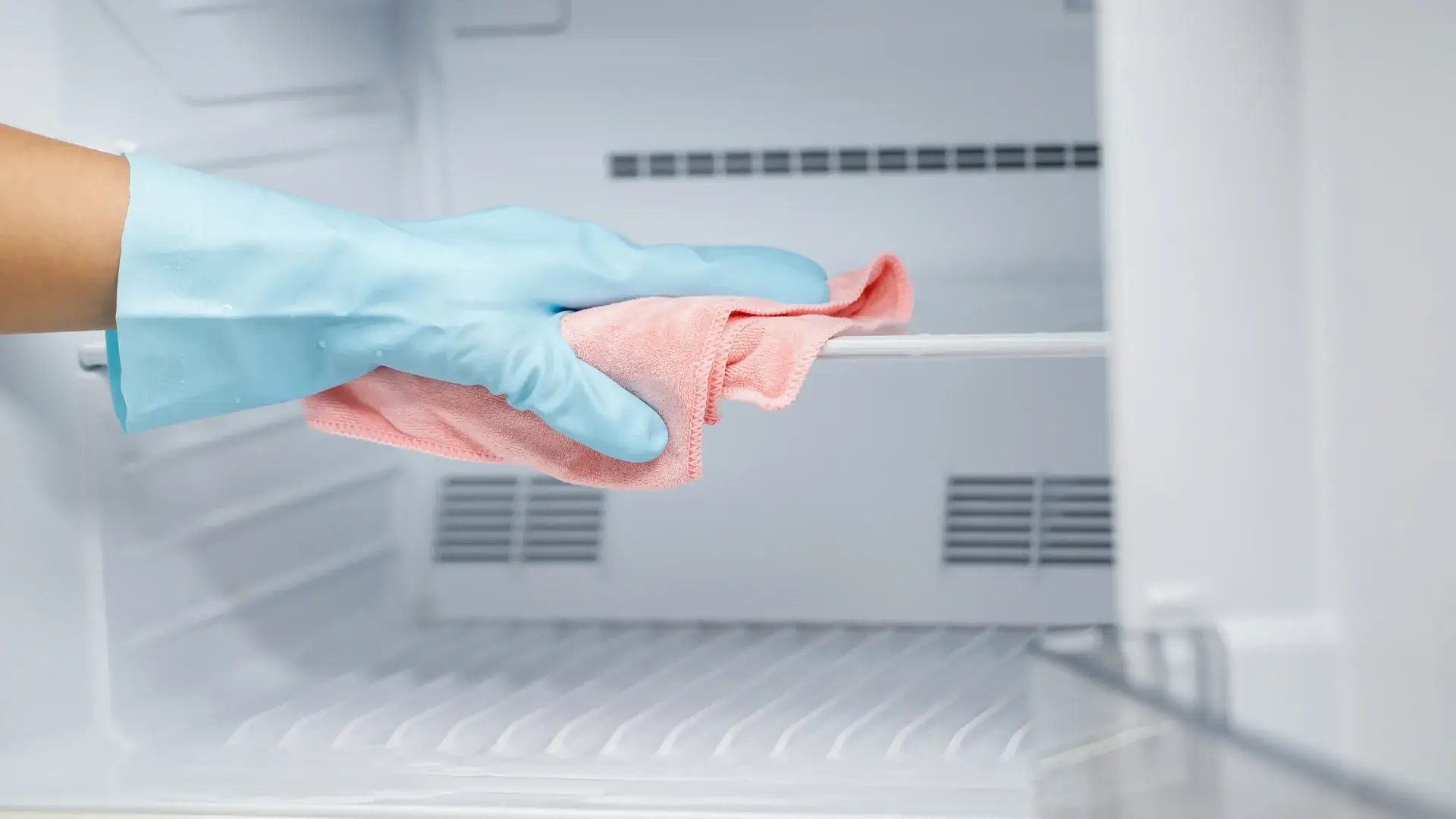 Cleaning staff wiping down refrigerator interior